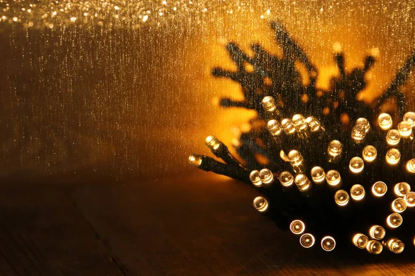 Navidad cálidas luces de guirnalda de oro sobre fondo rústico de madera. imagen filtrada — Foto de Stock
