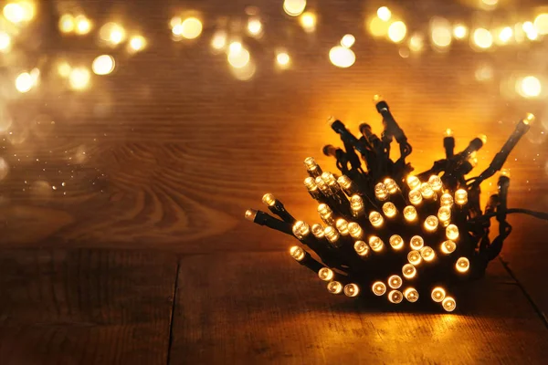 Kerstverlichting warme gouden garland op houten rustieke achtergrond. gefilterde afbeelding — Stockfoto