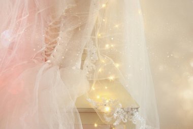 Güzel beyaz gelinlik ve peçe sandalyede altın garland ışıkları ile