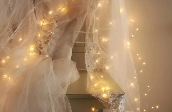 Belle robe de mariée blanche et voile sur chaise avec guirlande d'or lumières — Photo