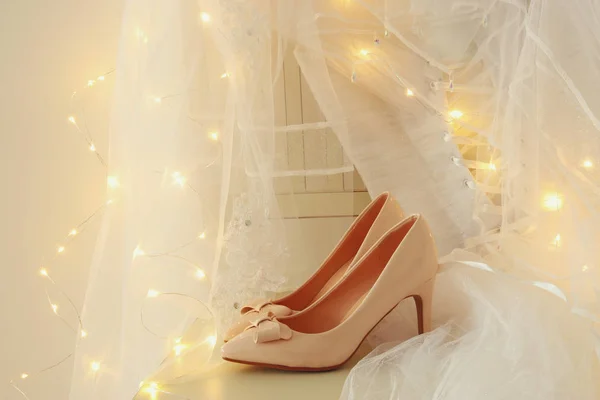 Schönes weißes Hochzeitskleid und Schleier auf Stuhl mit goldenem Lichterkranz — Stockfoto