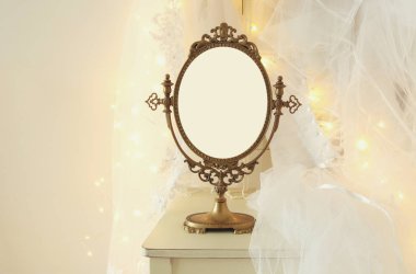 Eski vintage oval ayna ve güzel beyaz gelinlik ve peçe sandalyede altın garland ışıkları ile