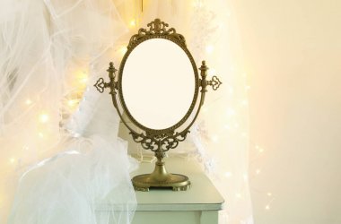 Eski vintage oval ayna ve güzel beyaz gelinlik ve peçe sandalyede altın garland ışıkları ile