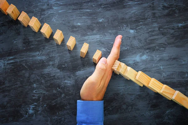 Egy férfi kéz megállítja a dominóhatást. végrehajtási és kockázatkezelési koncepció — Stock Fotó