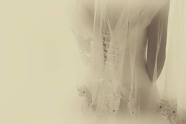 Beautiful bride with wedding dress and veil, from behind. Vintage Sepia style filter
