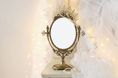 Eski vintage oval ayna ve güzel beyaz gelinlik ve peçe sandalyede altın garland ışıkları ile