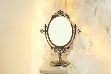 Eski vintage oval ayna ve güzel beyaz gelinlik ve peçe sandalyede altın garland ışıkları ile