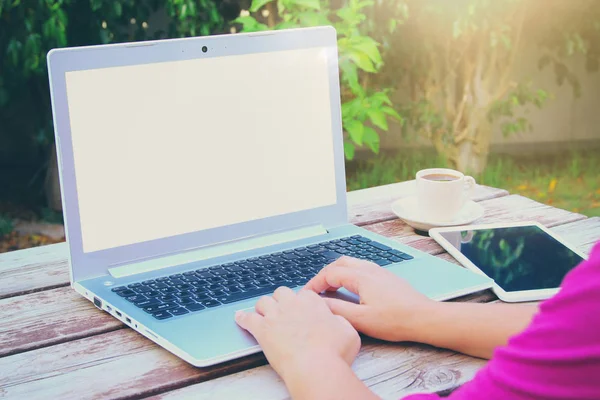 As mãos da mulher usando laptop com tela em branco na mesa de madeira ao ar livre no parque — Fotografia de Stock