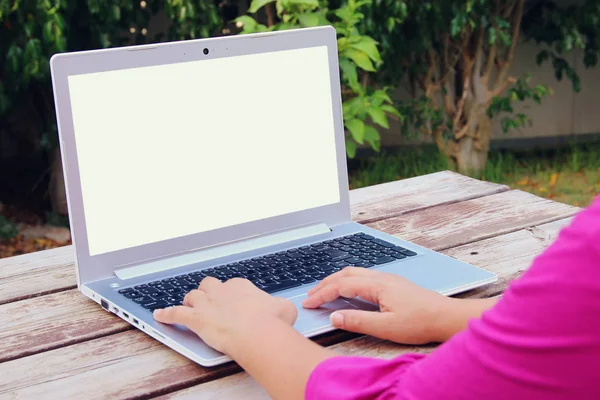 Las manos de la mujer usando el ordenador portátil con pantalla en blanco en la mesa de madera al aire libre en el parque —  Fotos de Stock