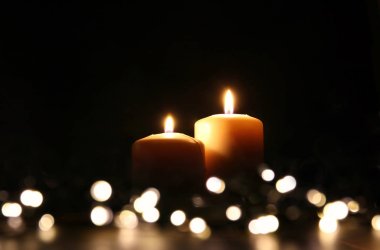 Bokeh parlak ışıklı siyah arka plan üzerinde yanan mumlar