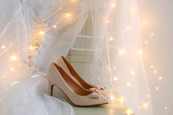 Красивое белое свадебное платье и вуаль на стуле с золотыми гирляндами — стоковое фото