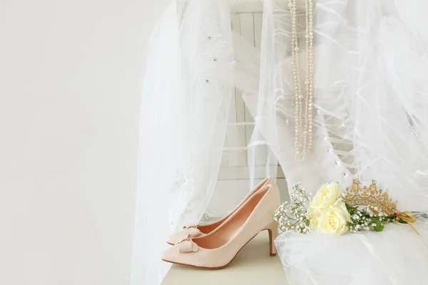 Hermoso vestido de novia blanco, zapatos, tiara de diamantes de oro y velo en la silla —  Fotos de Stock