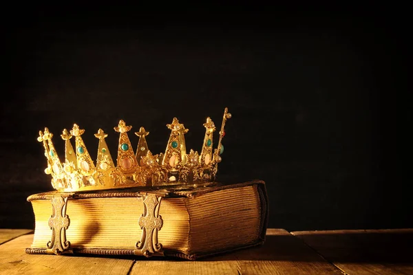 low key of queen/king crown on old book. vintage filtered. fantasy medieval period