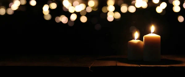 Brennende Kerzen auf schwarzem Hintergrund mit Bokeh-Glitzerlichtern. — Stockfoto