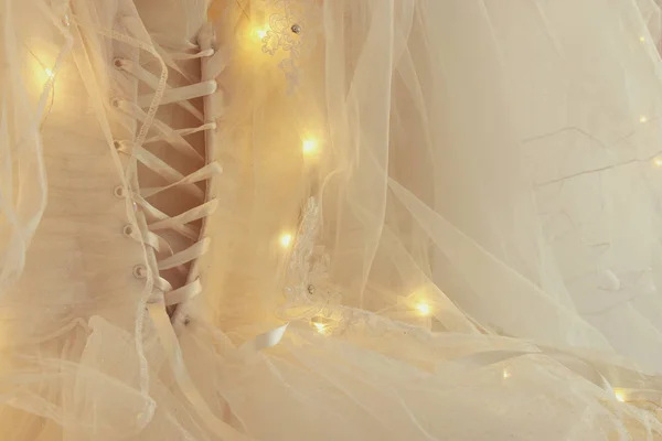 Bellissimo abito da sposa bianco e velo sulla sedia con luci ghirlanda — Foto Stock