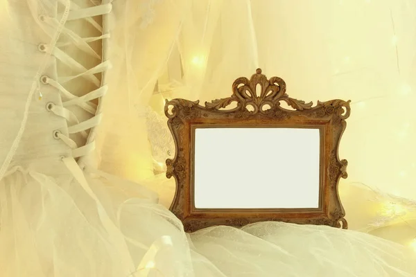 Antiguo espejo oval vintage y hermoso vestido de novia blanco y velo en silla con luces de guirnalda de oro —  Fotos de Stock