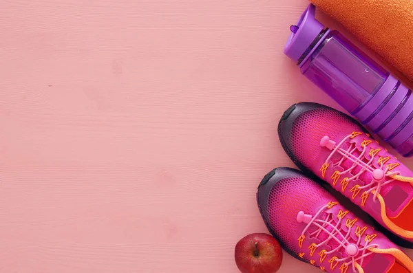 Concepto de fitness con botella de agua, toalla y mujer calzado deportivo rosa sobre fondo colorido —  Fotos de Stock