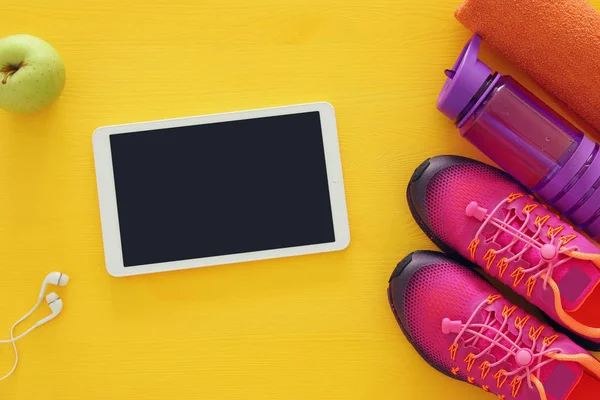 Fitness concept met flesje water, handdoek, tablet devise en vrouw roze sport schoenen over kleurrijke achtergrond — Stockfoto