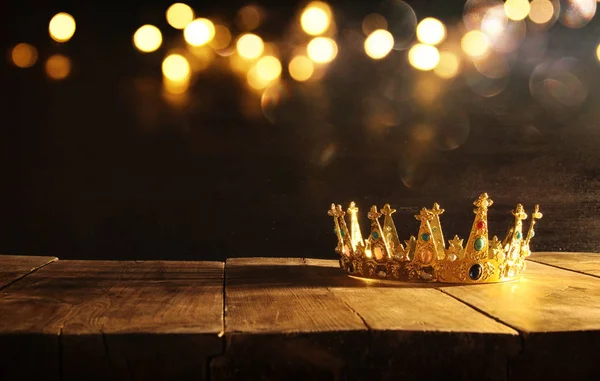 low key of queen/king crown over wooden table. vintage filtered. fantasy medieval period