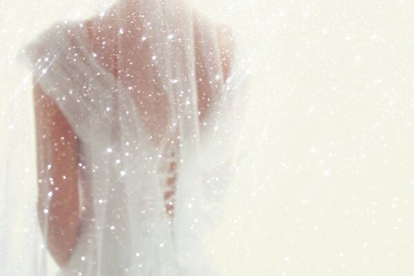 Dreamy abstract and blurry background of beautiful bride with wedding dress, from behind. Glitter overlay