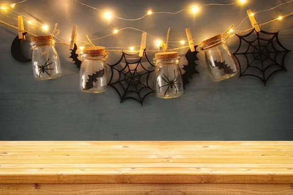 Halloween holiday concept. Empty old wooden table in front of masson jars with spiders and baths decorations — Stock Photo, Image