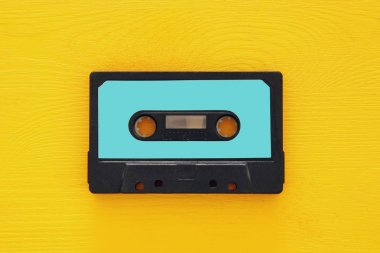 Retro cassette tape over yellow wooden table. top view. copy space clipart