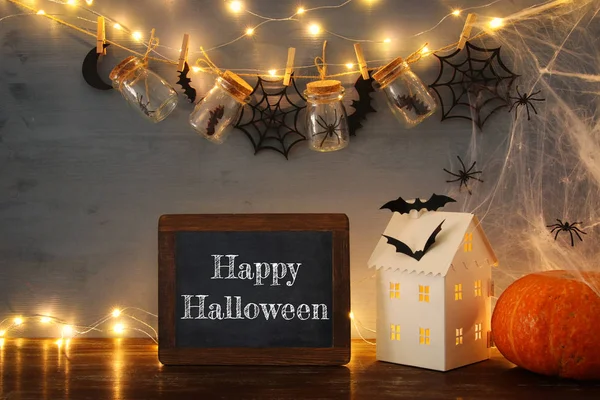 Halloween-Urlaubskonzept. Geheimnisvolles Haus mit Lichtern vor Massongläsern mit Spinnen und Badewannen — Stockfoto