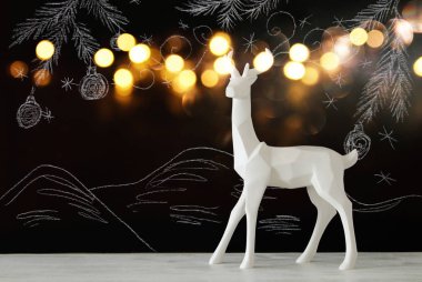 Kara tahta arka plan whith el üzerinde ahşap masa üzerinde beyaz Ren geyiği tebeşir illüstrasyonlar çizilmiş.