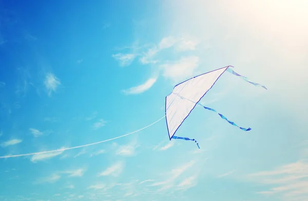 Colorful kite flying in the blue sky through the clouds. — Stock Photo, Image