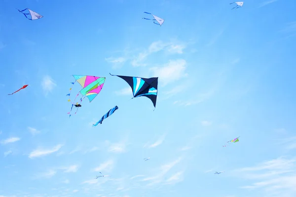 Pipa colorida voando no céu azul através das nuvens . — Fotografia de Stock