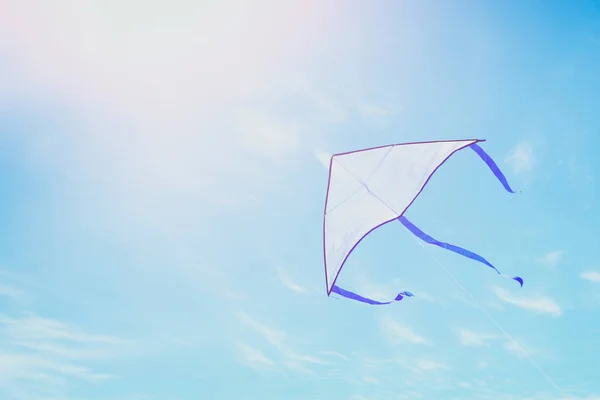 Pipa colorida voando no céu azul através das nuvens . — Fotografia de Stock