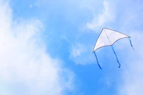 Colorful kite flying in the blue sky through the clouds. — Stock Photo, Image