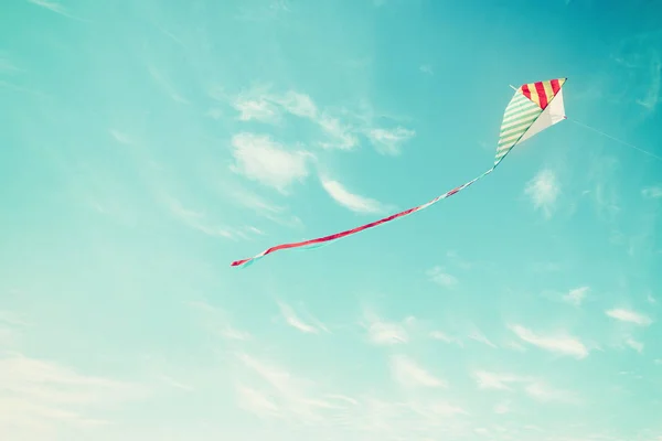 Pipa colorida voando no céu azul através das nuvens . — Fotografia de Stock