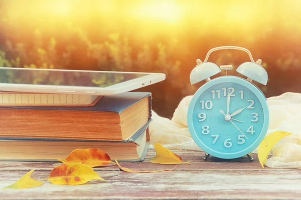 Imagen de otoño Cambio de Tiempo. Concepto de retroceso. Hojas secas y alarma vintage Reloj en mesa de madera al aire libre por la tarde —  Fotos de Stock