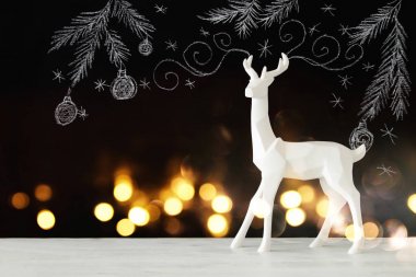 Kara tahta arka plan whith el üzerinde ahşap masa üzerinde beyaz Ren geyiği tebeşir illüstrasyonlar çizilmiş.