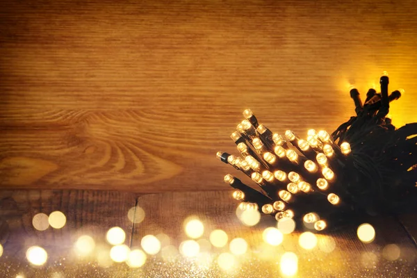 Navidad cálidas luces de guirnalda de oro sobre fondo rústico de madera. imagen filtrada — Foto de Stock