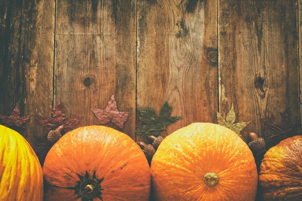 Pompoenen en herfst laat op houten achtergrond. Thanksgiving en halloween concept. Bovenaanzicht — Stockfoto