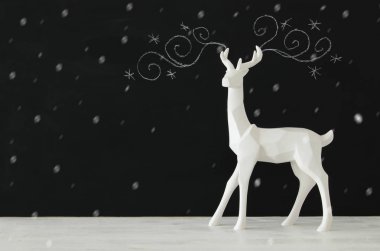 Kara tahta arka plan whith el üzerinde ahşap masa üzerinde beyaz Ren geyiği tebeşir illüstrasyonlar çizilmiş