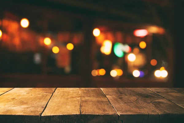 Image of wooden table in front of abstract blurred restaurant lights background — Stock Photo, Image