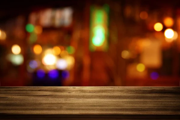 Image of wooden table in front of abstract blurred restaurant lights background — Stock Photo, Image