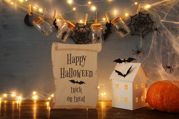 Halloween holiday concept. Mysterious house with lights in front of masson jars with spiders and baths