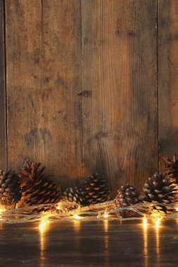 Tatil görüntü ile Noel altın çelenk ışık ve çam kozalakları ahşap arka plan üzerinde