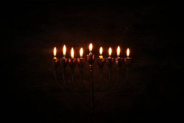 Low key image of jewish holiday Hanukkah background with menorah (traditional candelabra) and burning candles clipart