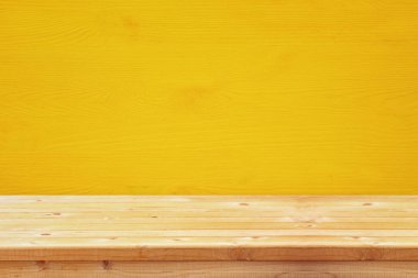 Sarı ahşap arka plan önünde boş bir tablo. Ürün görüntü montaj için