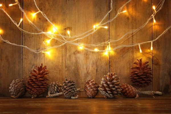 Tatil görüntü ile Noel altın çelenk ışık ve çam kozalakları ahşap arka plan üzerinde