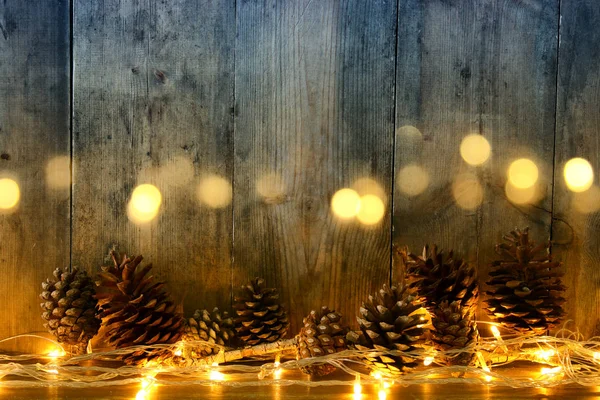 Holiday bild med gyllene krans julljus och kottar över trä bakgrund — Stockfoto