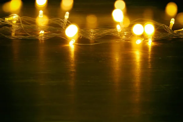 Navidad luces de guirnalda de oro caliente sobre el fondo de madera balck . — Foto de Stock