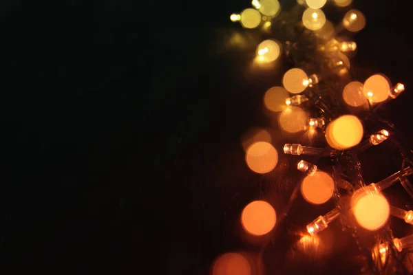 Varm guld garland julbelysning på balck trä bakgrund. Glitter överlägg. — Stockfoto