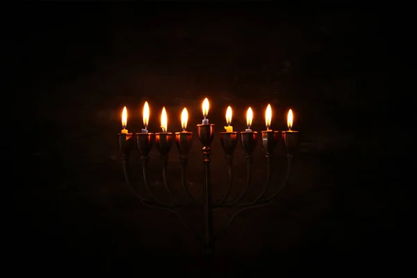 Low key image of jewish holiday Hanukkah background with menorah (traditional candelabra) and burning candles — Stock Photo, Image