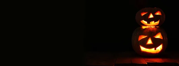 Calabaza de Halloween en la mesa de madera frente al espeluznante fondo oscuro. Jack o linterna — Foto de Stock
